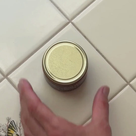 an overview shot of someone opening a jar of Vanilla Petal Tallow balm and rubbing it on their skin