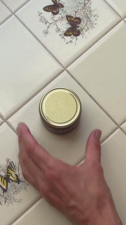 an overview shot of someone opening a jar of Vanilla Petal Tallow balm and rubbing it on their skin